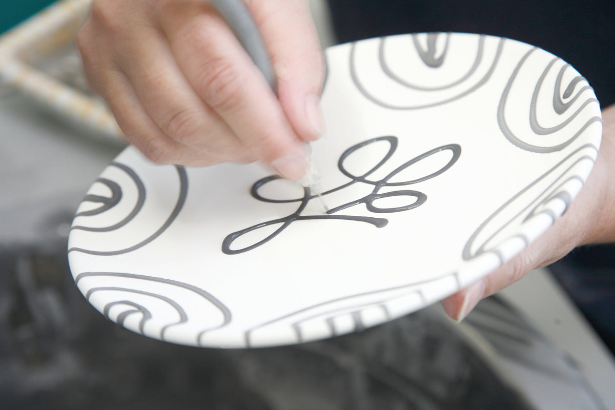A ceramic plate being decorated by hand at Gmundner Keramik